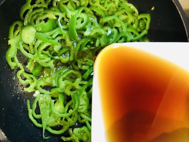 炒めているピーマンに麺つゆを入れる