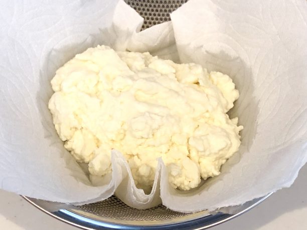 20分程根気よく混ぜると、ホイップの状態から固まってホエーとバターに分離するので、ざるにペーパータオルを乗せ、水分を切ります。