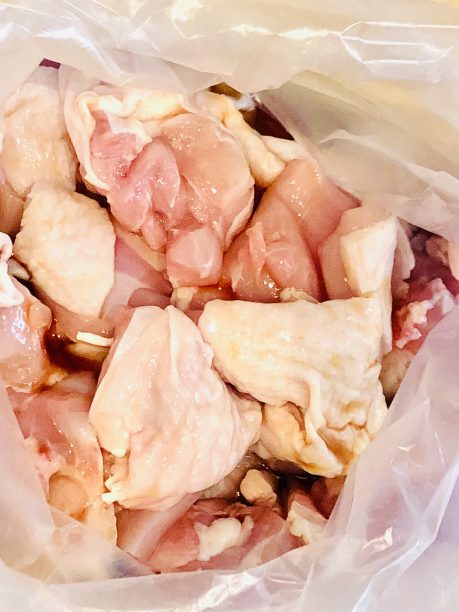 ポリ袋に鶏もも肉を入れ、酒と醤油を入れてよく揉み込みます。