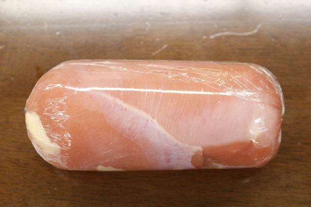 広げたラップの上に鶏むね肉を置き、キャンディーを包むように包み両端をとめます。