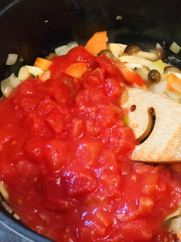 野菜がしんなりしてきたら、トマト缶、コンソメを入れて蓋をして一煮立ちさせます。
