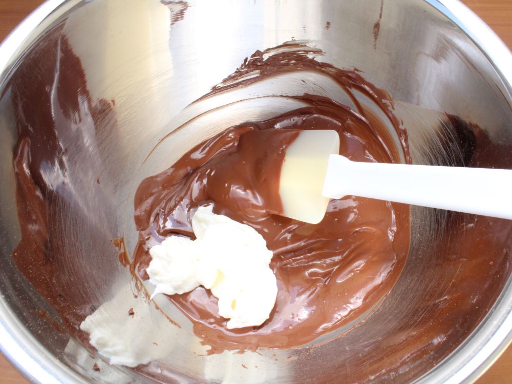 チョコレートが溶けたら、水切りヨーグルト、レーズンを加えてよく混ぜます。（お好みでラム酒を加えてください）